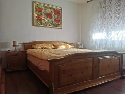 a bedroom with a wooden bed with a painting on the wall at House Leyla in Bihać