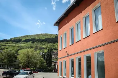 a red building with cars parked in front of it at Becar Pyramid Rooms in Visoko