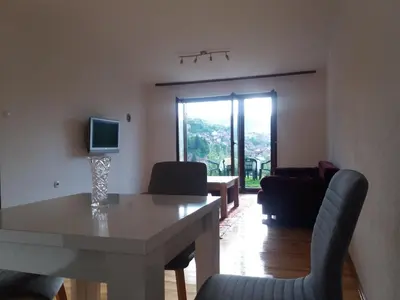 a living room with a table and chairs and a television at Honey Apartments in Visoko