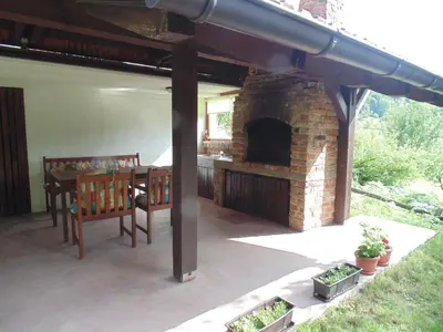 a patio with a brick fireplace and a table and bench at Holiday Home Alibegović in Visoko