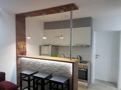 a kitchen with a counter with stools in it at Apartman 
