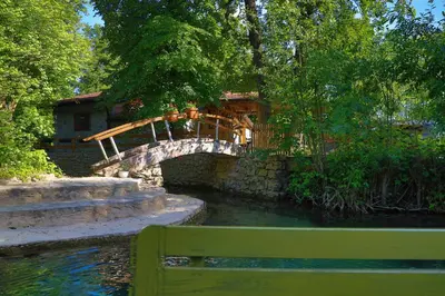 a bridge over a river with a green bench at Apartment Green Lagoon in Bihać