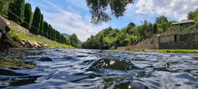 a river flowing down a road with trees at holiday home RIVER HOUSE in Jajce
