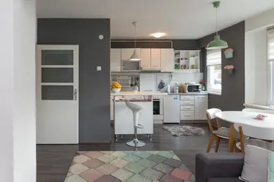 a kitchen with white cabinets and a table and a dining room at Apartment Amra in Visoko