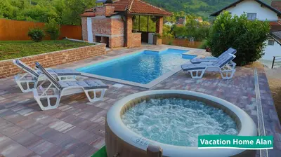 a swimming pool with two chairs and a hot tub at Vacation home Alan 2 in Kulen Vakuf