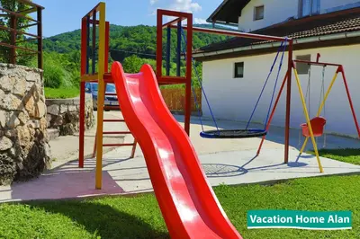 a playground with a red slide and swings at Vacation home Alan 2 in Kulen Vakuf