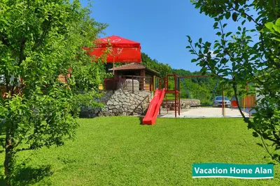 a playground in a yard with a red slide at Vacation home Alan 2 in Kulen Vakuf