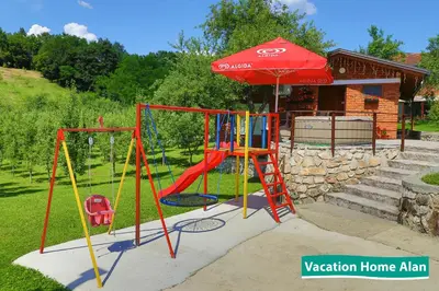 a playground with a swing set and an umbrella at Vacation home Alan 2 in Kulen Vakuf