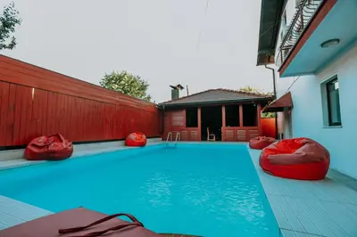 a swimming pool with red chairs and a house at Holiday Home Ajna in Bihać
