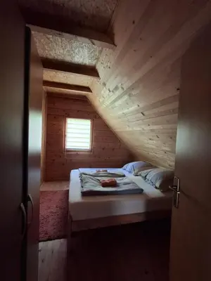 a bed in a wooden room with a window at Apartman Relax in Nature in Jajce