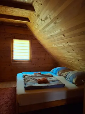 a bed in a room with a wooden ceiling at Apartman Relax in Nature in Jajce