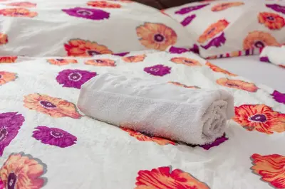 a white towel laying on a bed with flowers at Apartment Resaa in Bihać