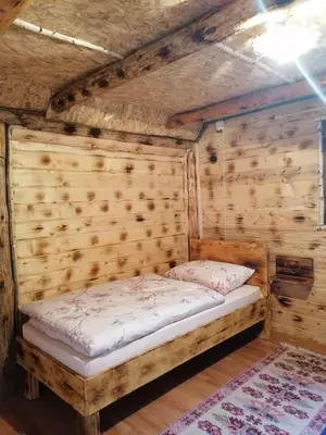a small bed in a room with wooden walls at Etno kuce Miljevic in Šipovo