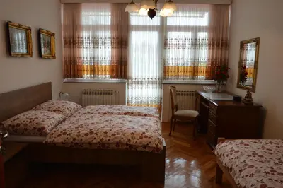 a bedroom with two beds and a desk and windows at Apartment Sarah in Bihać