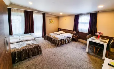 a bedroom with two beds and a table and windows at Apartments Alf - Om in Banja Luka