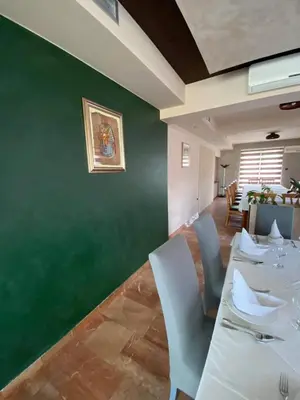 a dining room with a table and chairs and a green wall at Motel Tiron in Kakanj