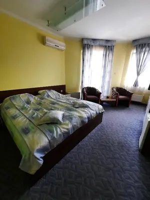 a bedroom with a bed and two chairs and windows at Motel Tiron in Kakanj