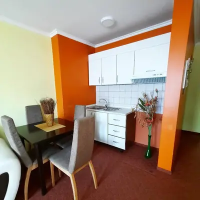 a small kitchen with a table and chairs and orange walls at Motel Tiron in Kakanj