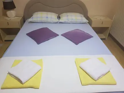 a white bed with purple and yellow pillows on it at Guesthouse 