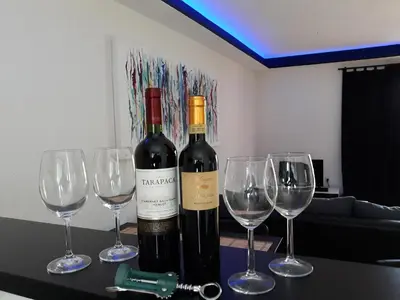 a table with two bottles of wine and three wine glasses at Holidayhouse Visoko in Visoko
