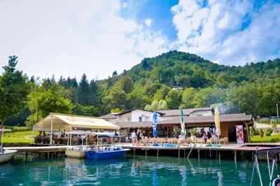 a group of people sitting on a dock in the water at Motel Plaza in Jajce