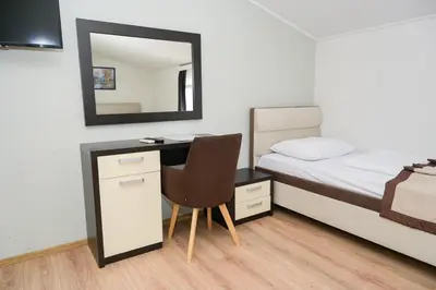 a bedroom with a bed and a desk with a mirror at Motel Plaza in Jajce