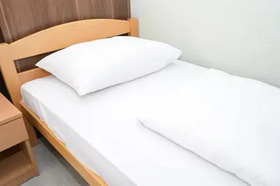 two beds in a room with white sheets and a pillow at Motel Plaza in Jajce