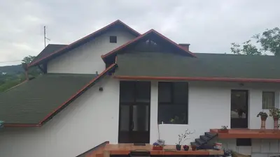 a white house with a green roof at Apartments Emir in Tuzla