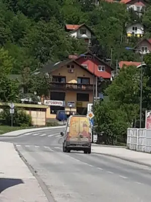 a small car driving down a street with a building at Apartments Emir in Tuzla