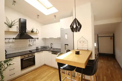a kitchen with white cabinets and a wooden table at La Paloma Blanca in Tuzla