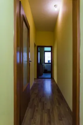 an empty hallway with yellow walls and wooden floors at Apartments & Rooms Fountain in Bihać