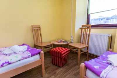 a room with two beds and a table and chairs at Apartments & Rooms Fountain in Bihać
