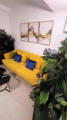 a yellow couch with blue pillows in a living room at Apartmani Abbazia in Banja Luka
