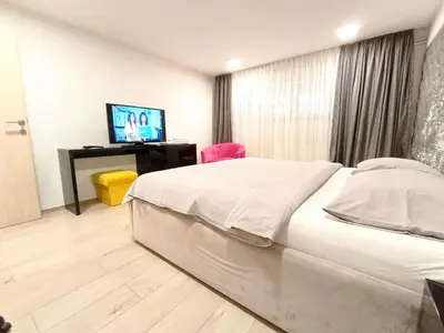 a bedroom with a bed and a desk and a television at Apartmani Abbazia in Banja Luka