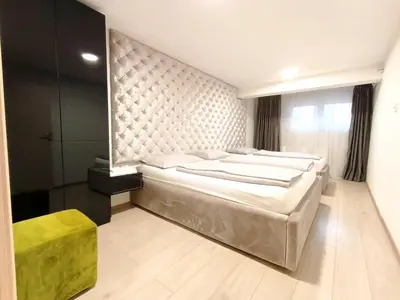 a bedroom with a large bed and a yellow stool at Apartmani Abbazia in Banja Luka