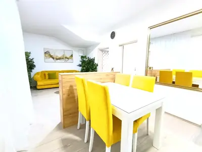 a dining room with yellow chairs and a white table at Apartmani Abbazia in Banja Luka