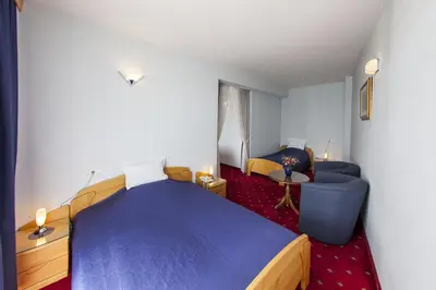 a bedroom with a blue bed and a couch and a table at Hotel Senad od Bosne in Prokosovići