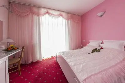 a pink bedroom with a bed and a desk and a window at Hotel Senad od Bosne in Prokosovići