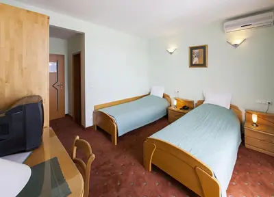 a hotel room with two beds and a table and a tv at Hotel Senad od Bosne in Prokosovići
