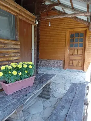 a porch of a house with a wooden door and flowers at Piramida Mjeseca in Visoko