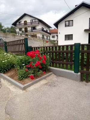 a fence with red flowers in front of a house at Holiday Home Nana in Bugojno