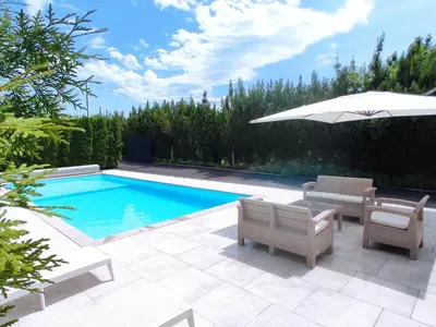 a swimming pool with chairs and an umbrella next to it at Natural Cottage Una in Bihać