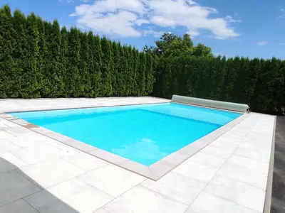 a swimming pool in front of a hedge at Natural Cottage Una in Bihać