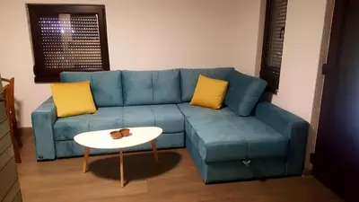 a blue couch with two yellow pillows and a table at Natural Cottage Una in Bihać