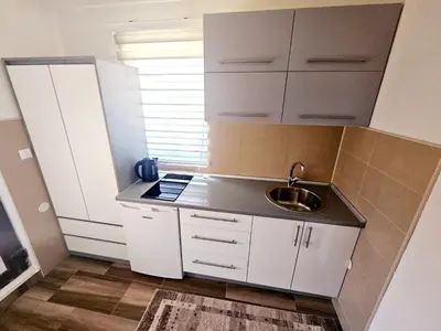 a small kitchen with white cabinets and a sink at AMAI Exclusive in Tuzla