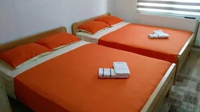 two beds in a room with orange sheets and towels at AMAI Exclusive in Tuzla