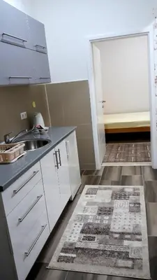 a kitchen with white cabinets and a sink and a door at AMAI Exclusive in Tuzla
