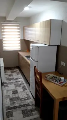 a kitchen with a table and a white refrigerator at AMAI Exclusive in Tuzla