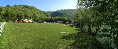 a field of grass with tents in the background at Camp Vrbas in Rekavice