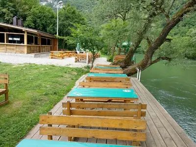a row of wooden benches next to a river at Camp Vrbas in Rekavice